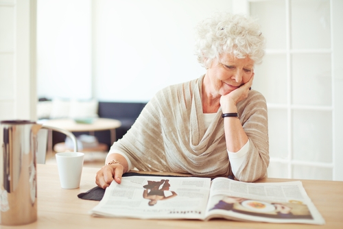 Older Woman Smiling and Reading Newspaper, Free of Cataracts