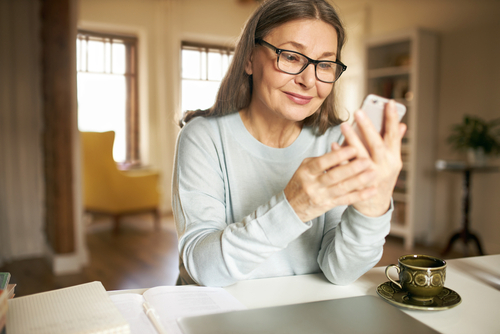 An elderly woman smiling and looking at her phone