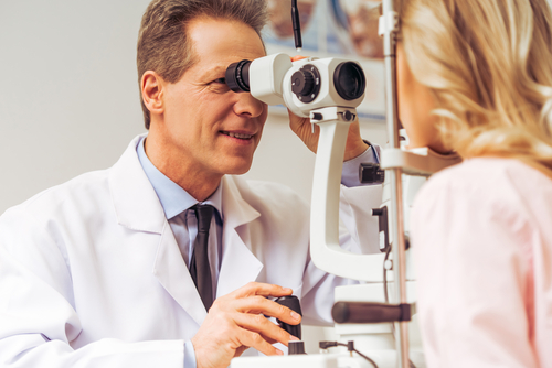 Male eye doctor performing eye exam on female patient