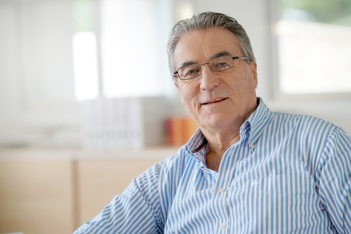 older man wearing glasses and smiling for his picture being taken