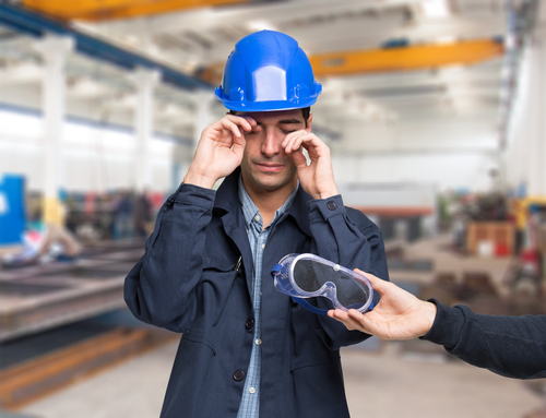 Man rubbing his eyes and being handed safety goggles