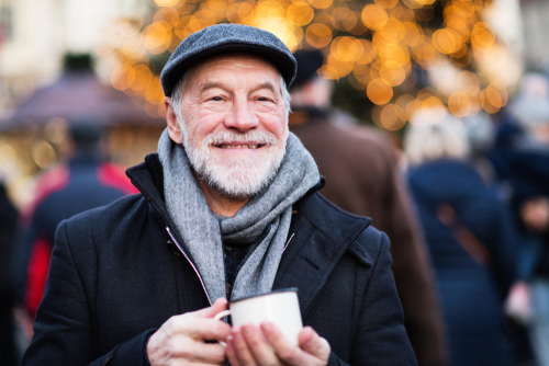 man smiling while holding cup of coffee